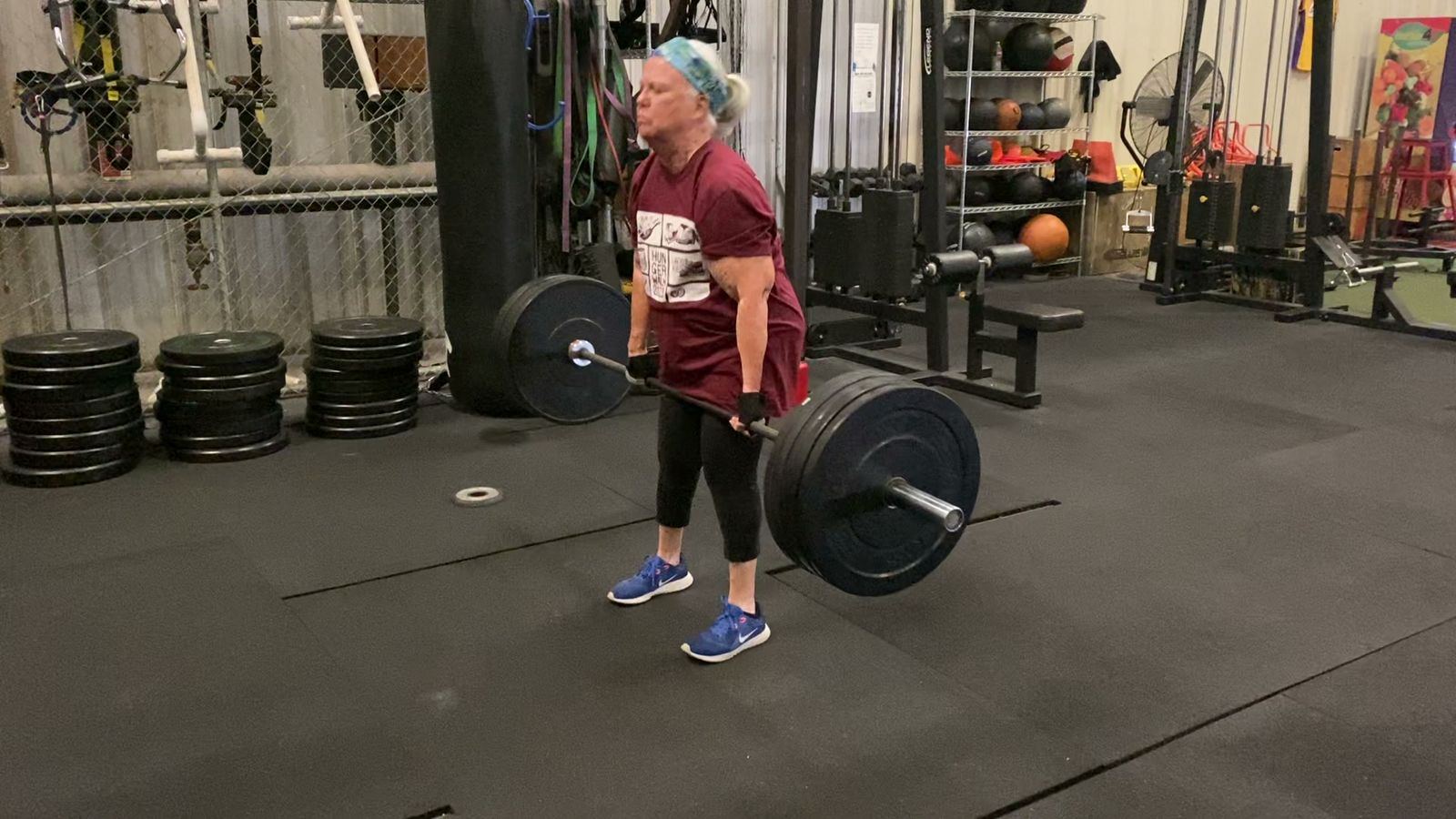 Senior client completing a barbell deadlift with proper form